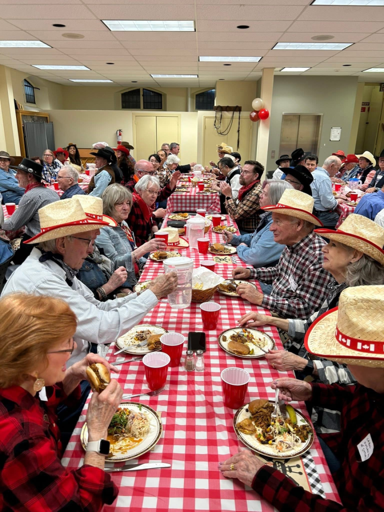 people in western dress eating at a long ranch-style table